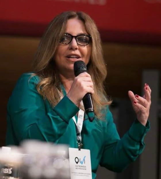 Claudia Fernandes falando ao microfone em painel de evento da ABA