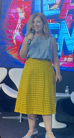 Claudia Fernandes de pé no palco, com microfone