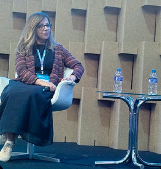 Claudia Fernandes sentada em painel de evento