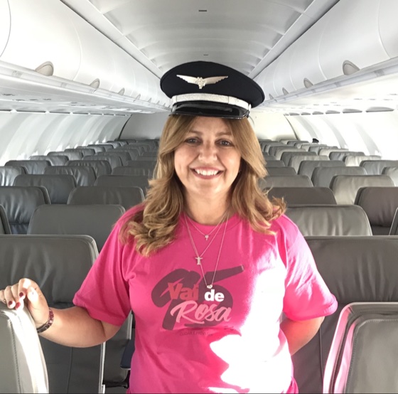 Claudia Fernandes a bordo de um avião da Azul com a camiseta rosa da campanha Vai de Rosa
